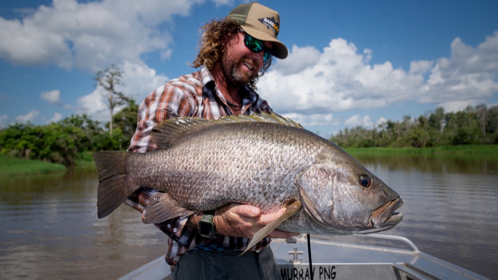 Watty grinning with a Papua New Guinea black bass on the Lake Murray boat