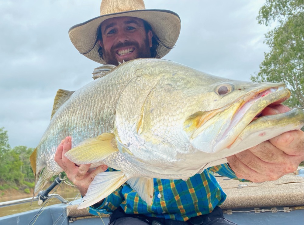 Watty grinning behind a huge silver barramundi filling the frame
