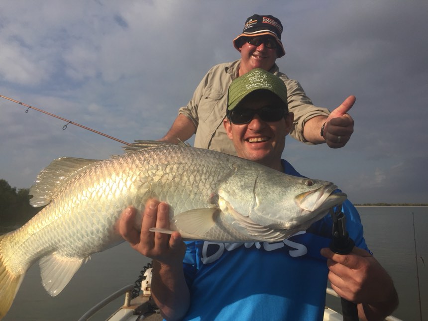 Guest grinning with a barra boatside