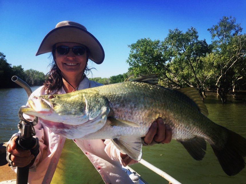 Angler in a river with a golden barra