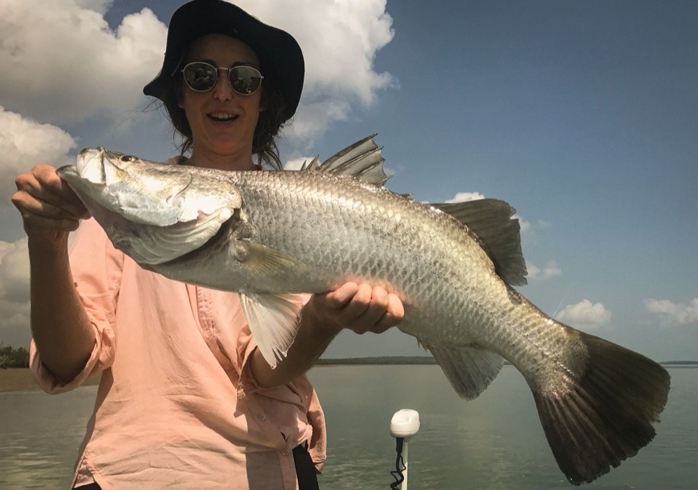 Guest holding a chrome barramundi on open water