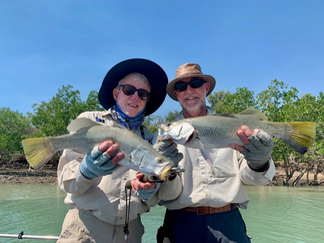 Two anglers with a pair of barramundi on clear water