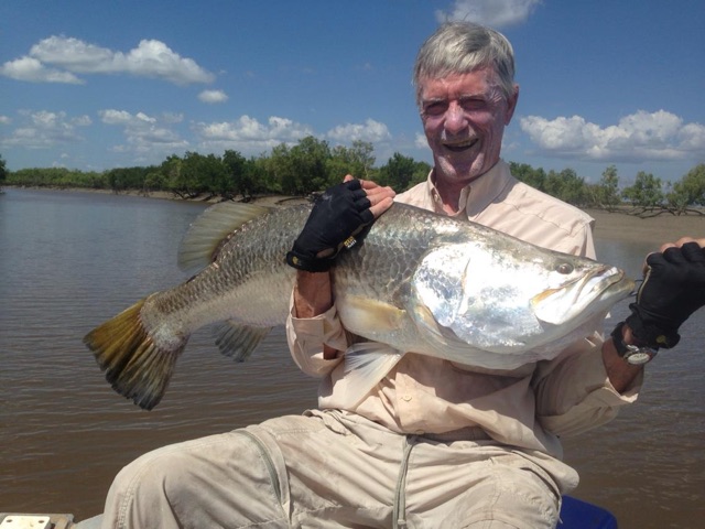 Grinning angler with a thick-shouldered barra in the boat