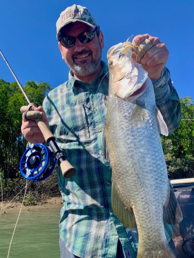 Fly angler lifting a barramundi clear of the water in Bynoe Harbour, rod still loaded