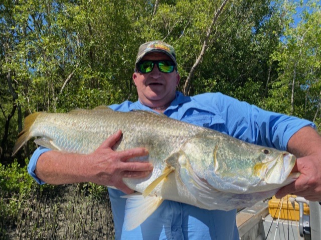 Angler with a broad silver barra on a bright dry-season day