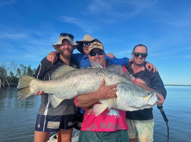Four mates crowded round a big barra on the front deck