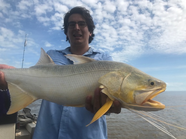 Young angler holding a king threadfin salmon boatside during the run-off