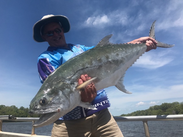 Queenfish held out over blue water